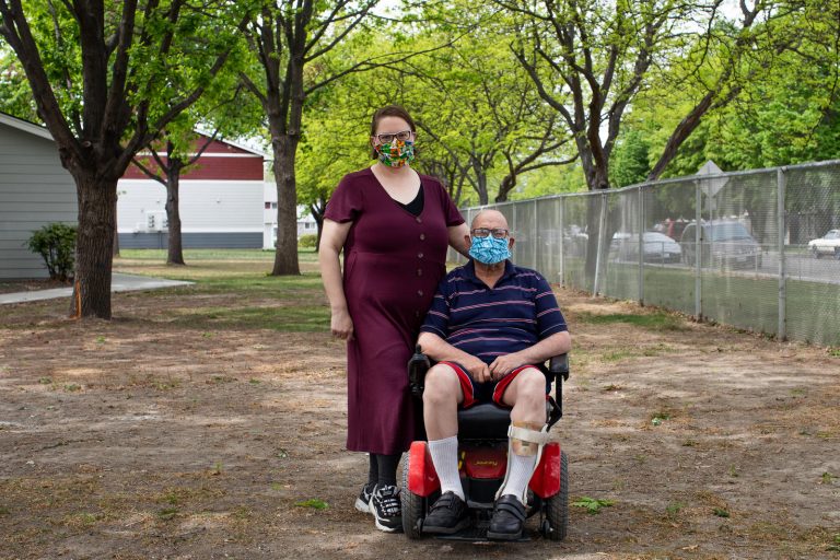 Desirae Hernandez, a caregiver in Kennewick, Benton County, stands with her client Scott Philbeck, 60, at his apartment complex, April 29, 2020. "It's been hard," says Philbeck, looking to Hernandez for suppport with expressing how things have been lately. "He doesn't get out much these days and the anxiety from that can be debilitating I've noticed. The masks create this additional layer of claustrophobic anxiety for my clients as well." (Matt M. McKnight/Crosscut)