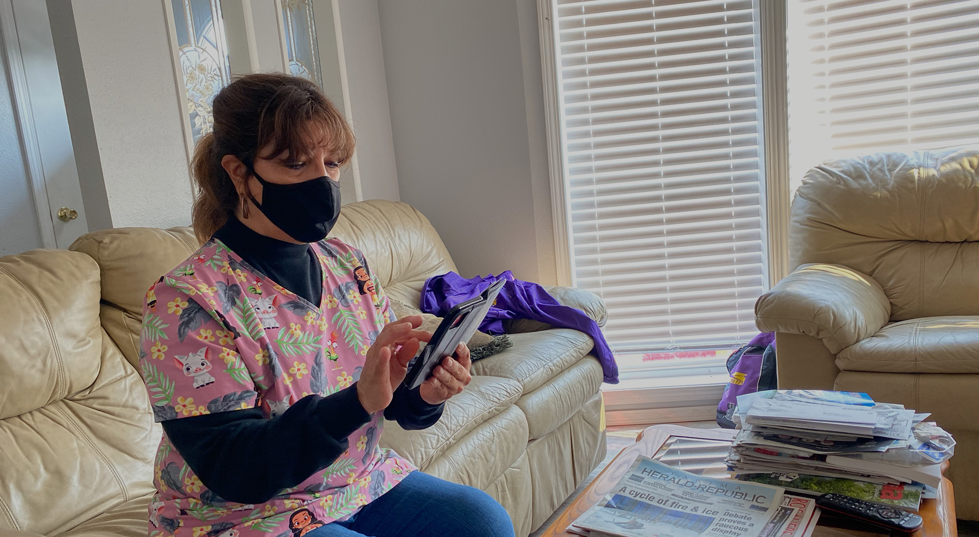 A caregiver wearing a mask looks at their phone