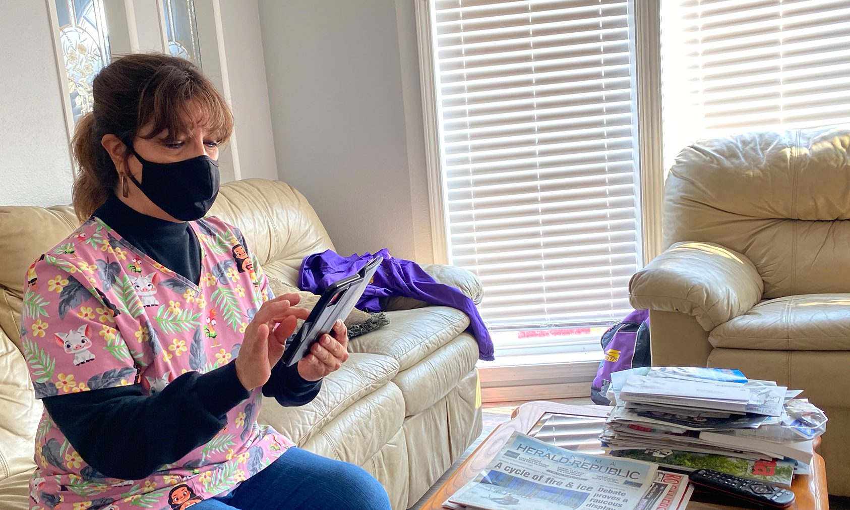 A caregiver wearing a mask looks at their phone