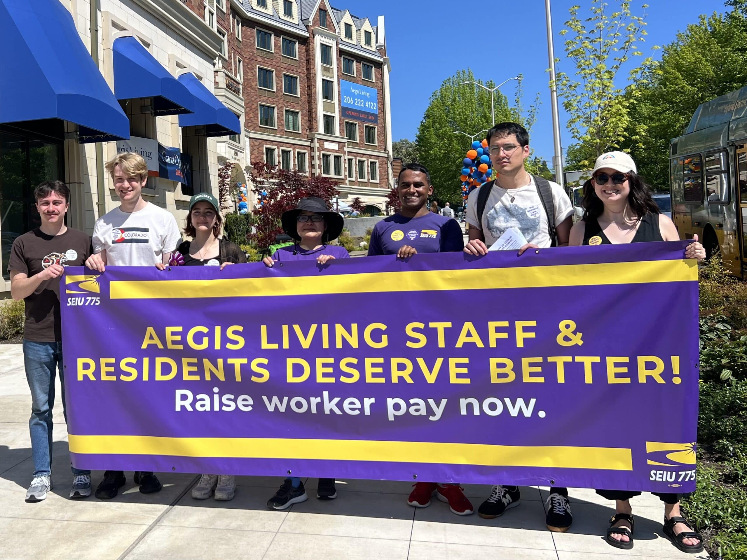 Workers at Aegis Living hold a sign that says "Aegis Living Staff and Residents Deserve Better"